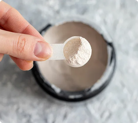 One scoop of FLOW powder being added to a glass of water